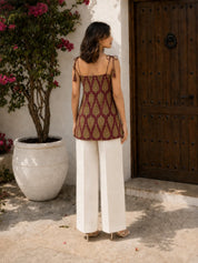 Kurti corto de algodón con nudo atado al hombro, color granate y estampado de hojas.